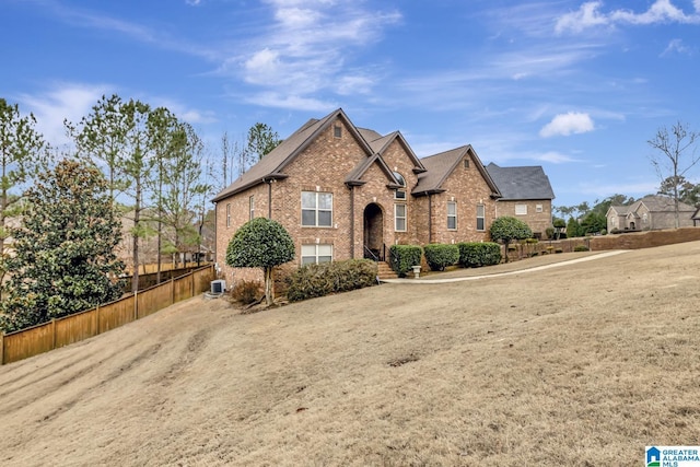 view of front of house with brick siding, fence, and central air condition unit