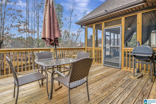 wooden deck with outdoor dining space, a sunroom, and area for grilling