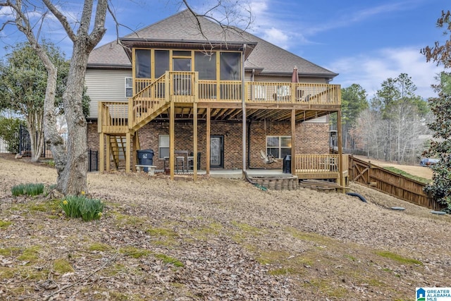 back of house with a patio, brick siding, a sunroom, roof with shingles, and stairway