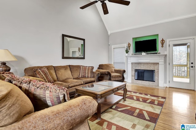 living area with a fireplace, crown molding, a ceiling fan, wood finished floors, and high vaulted ceiling