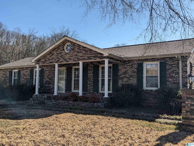 ranch-style house featuring roof with shingles and brick siding