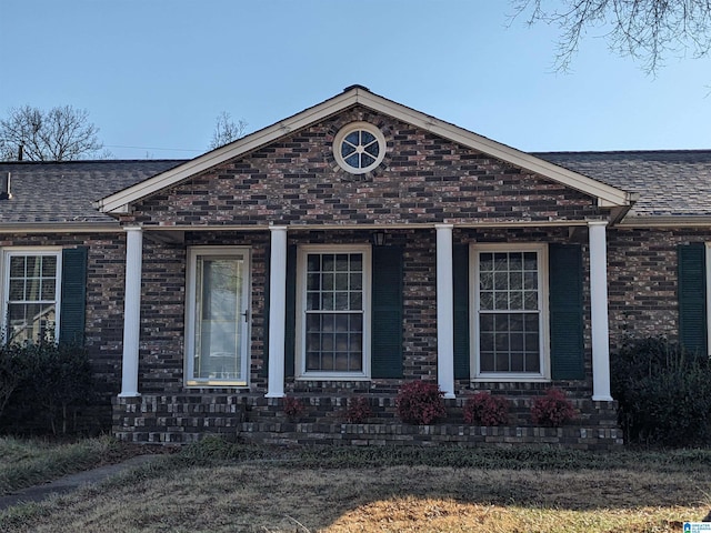 view of front facade with a shingled roof and brick siding