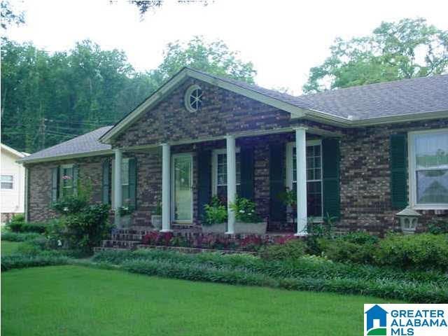 ranch-style house featuring covered porch and a front lawn