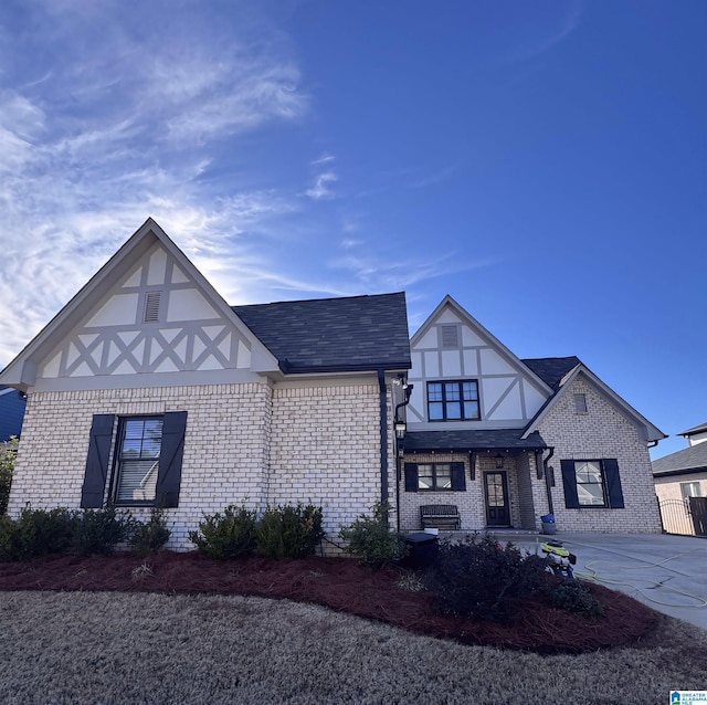 tudor house featuring concrete driveway and brick siding