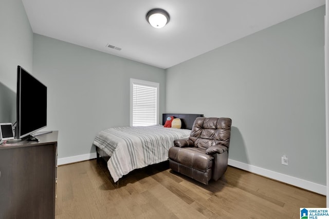 bedroom featuring visible vents, baseboards, and wood finished floors