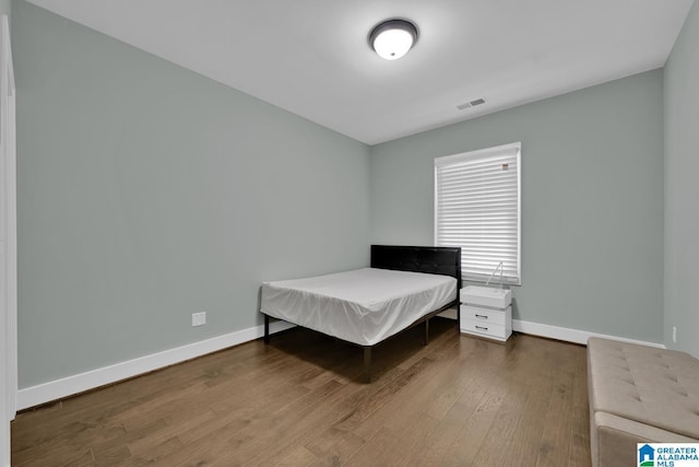 bedroom featuring visible vents, baseboards, and wood finished floors