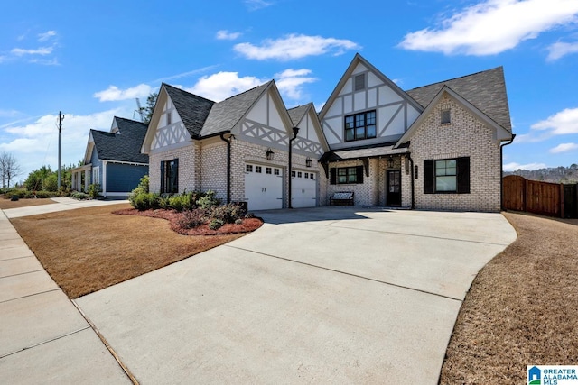 english style home featuring brick siding, driveway, roof with shingles, and fence