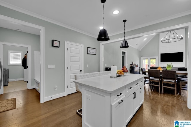 kitchen with white cabinets, a center island, crown molding, and dark wood-style flooring