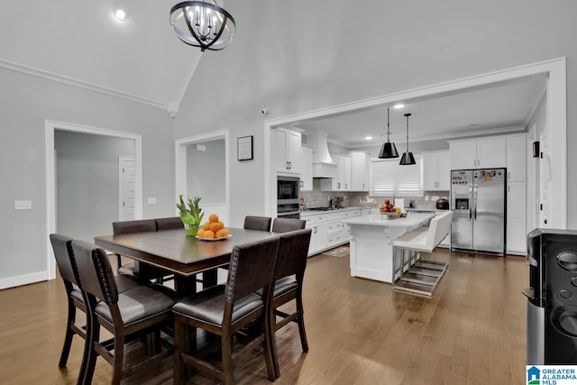 dining room with dark wood-type flooring, a notable chandelier, baseboards, and ornamental molding