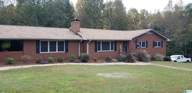 ranch-style house featuring brick siding, a chimney, and a front yard