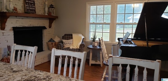 sitting room featuring a brick fireplace, plenty of natural light, and wood finished floors