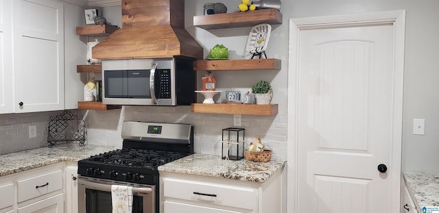 kitchen featuring open shelves, tasteful backsplash, custom range hood, appliances with stainless steel finishes, and white cabinetry