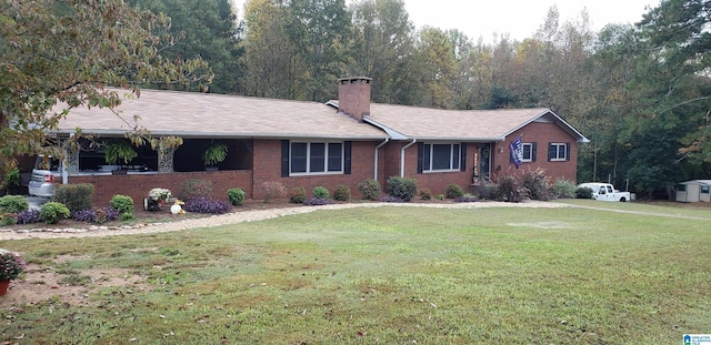 ranch-style house featuring a front yard, brick siding, and a chimney