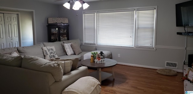 living area with ceiling fan, wood finished floors, visible vents, and baseboards