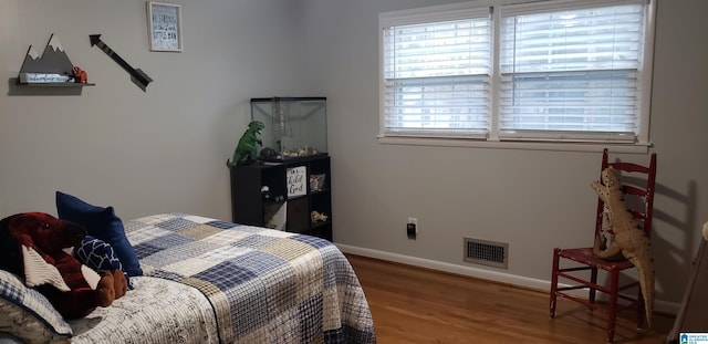 bedroom with wood finished floors, visible vents, and baseboards