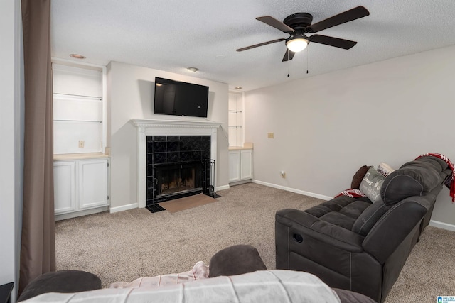 living area with a textured ceiling, a tiled fireplace, carpet flooring, and baseboards