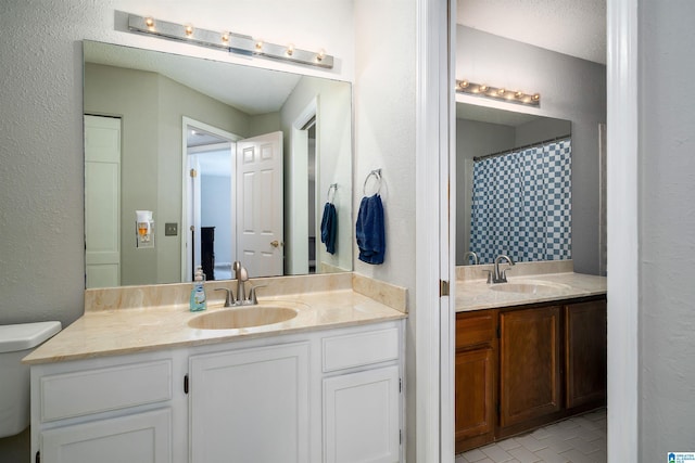 full bathroom with two vanities, a sink, and toilet