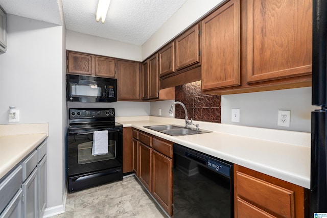 kitchen featuring tasteful backsplash, light countertops, a textured ceiling, black appliances, and a sink