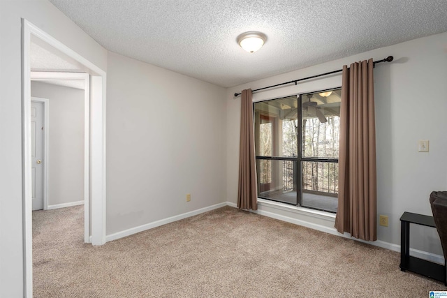 empty room with carpet flooring, a textured ceiling, and baseboards