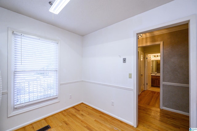 spare room featuring light wood-style floors, baseboards, and visible vents