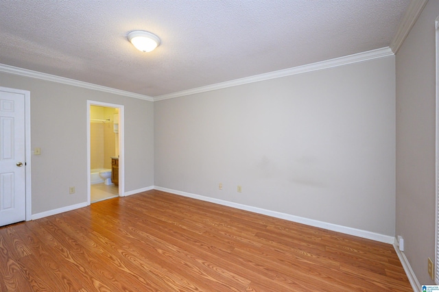 spare room featuring a textured ceiling, light wood finished floors, ornamental molding, and baseboards