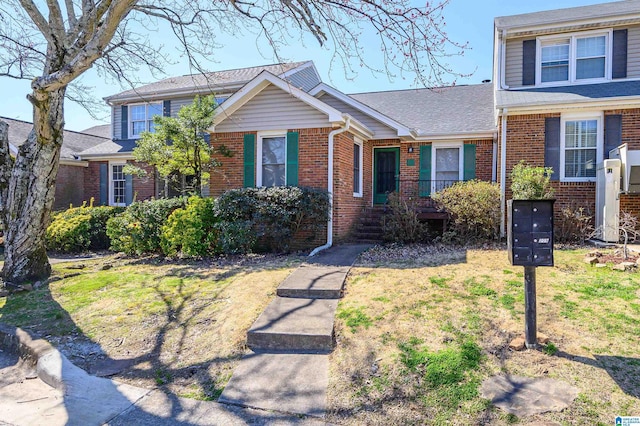 view of front of home featuring a shingled roof, brick siding, and a front lawn