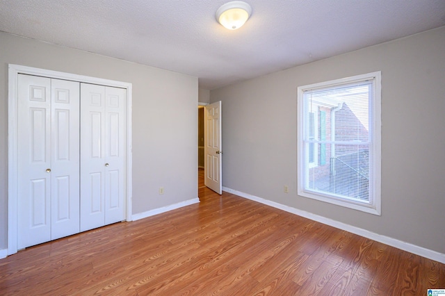 unfurnished bedroom with light wood-type flooring, baseboards, and a closet