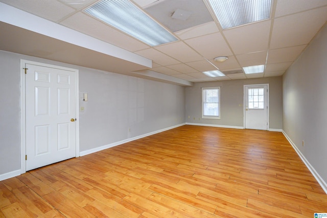 spare room with a paneled ceiling, baseboards, and light wood finished floors