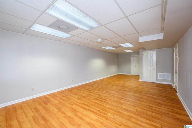 empty room with baseboards, a drop ceiling, visible vents, and light wood-style floors