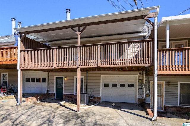 back of property featuring a garage, central AC, and brick siding