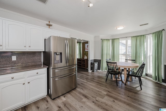 kitchen with white cabinets, light wood-type flooring, ornamental molding, and stainless steel refrigerator with ice dispenser