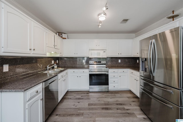 kitchen with stainless steel appliances, a sink, visible vents, decorative backsplash, and dark countertops