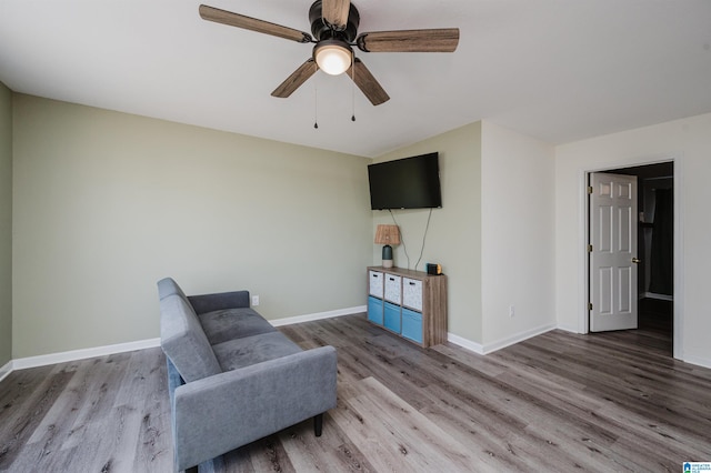 sitting room with a ceiling fan, baseboards, and wood finished floors