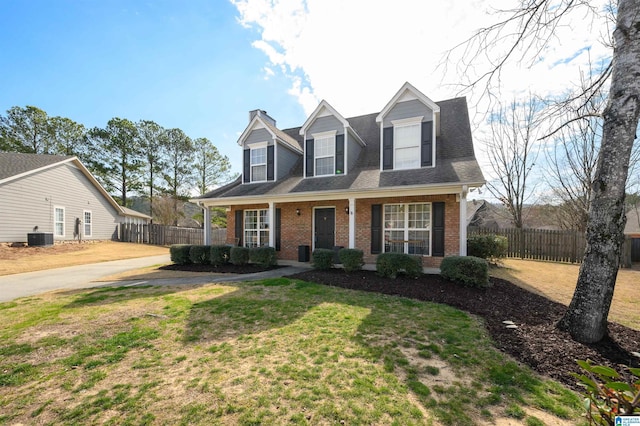 cape cod home with brick siding, fence, a front lawn, and central air condition unit