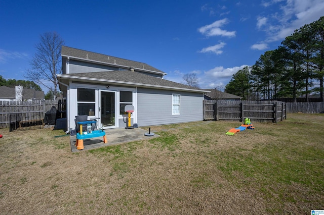 rear view of house with a shingled roof, a fenced backyard, and a lawn