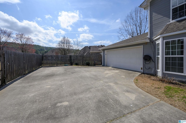 view of patio featuring a garage, driveway, and fence