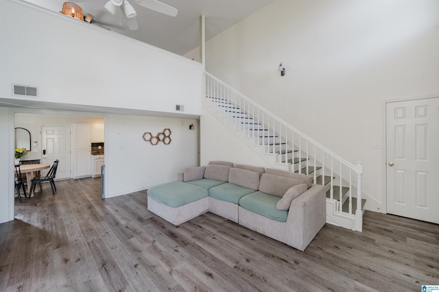 living room featuring a high ceiling, stairs, visible vents, and wood finished floors