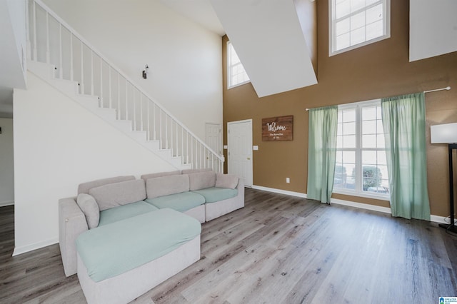 living area with a wealth of natural light, wood finished floors, baseboards, and stairs