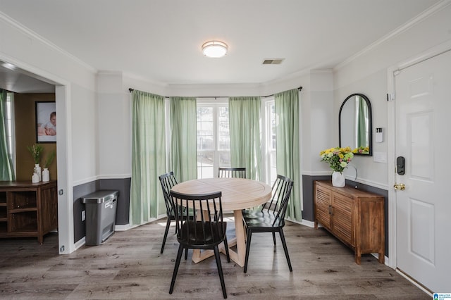 dining space with baseboards, visible vents, ornamental molding, and wood finished floors