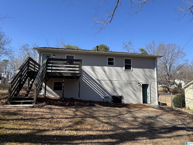 rear view of property featuring stairs, a deck, and fence