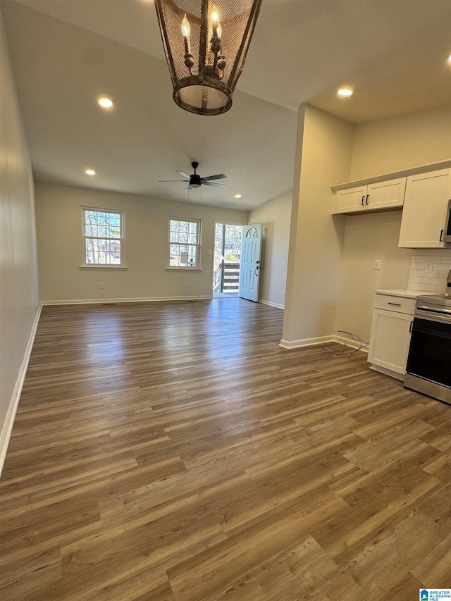 interior space featuring ceiling fan with notable chandelier, recessed lighting, wood finished floors, and baseboards