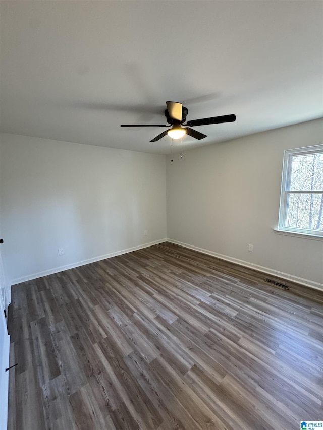 spare room featuring dark wood-style flooring, visible vents, ceiling fan, and baseboards