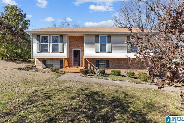 split foyer home with brick siding, an attached garage, and a front lawn