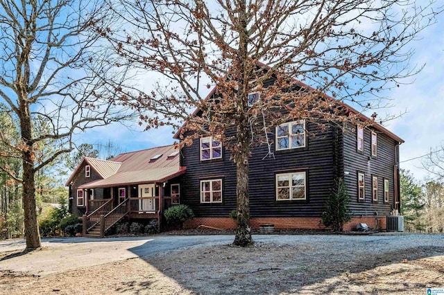 view of front of house featuring metal roof, a porch, central AC unit, driveway, and crawl space