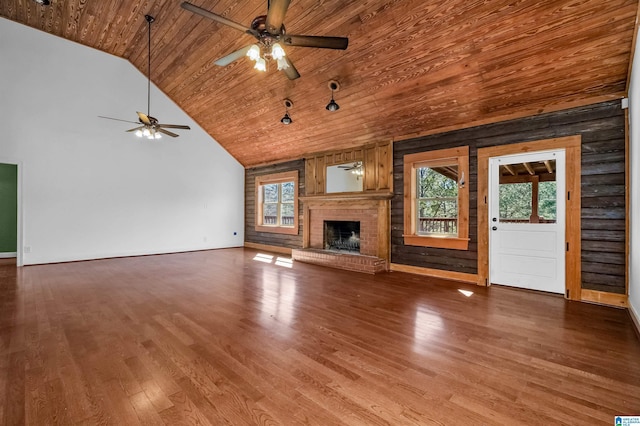 unfurnished living room with a wealth of natural light, a brick fireplace, wooden ceiling, and wood finished floors