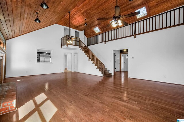 unfurnished living room featuring a skylight, wooden ceiling, stairway, wood finished floors, and a fireplace