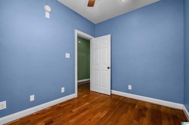 unfurnished room featuring wood finished floors, a ceiling fan, and baseboards