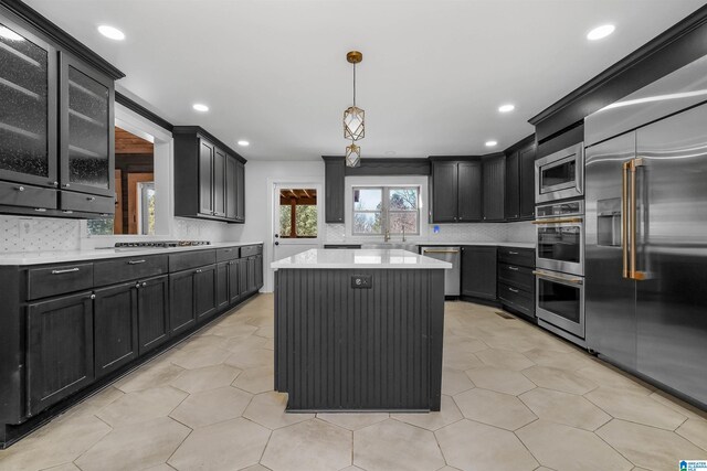 kitchen with dark cabinets, a kitchen island, and built in appliances