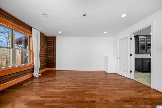 empty room featuring rustic walls, baseboards, visible vents, wood finished floors, and recessed lighting