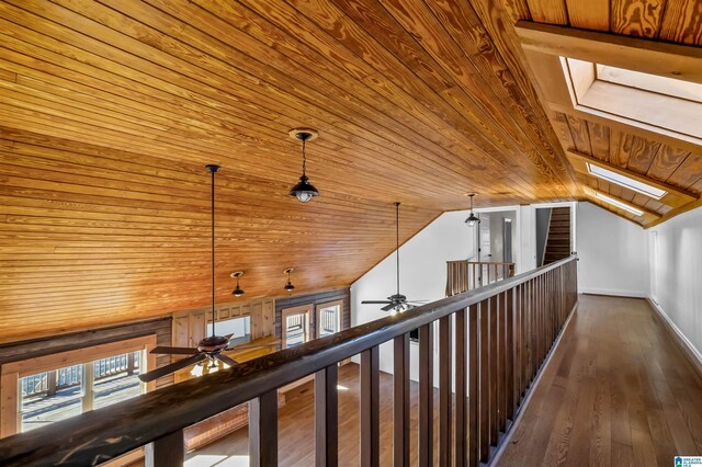 corridor featuring vaulted ceiling with skylight, dark wood-type flooring, wooden ceiling, and baseboards